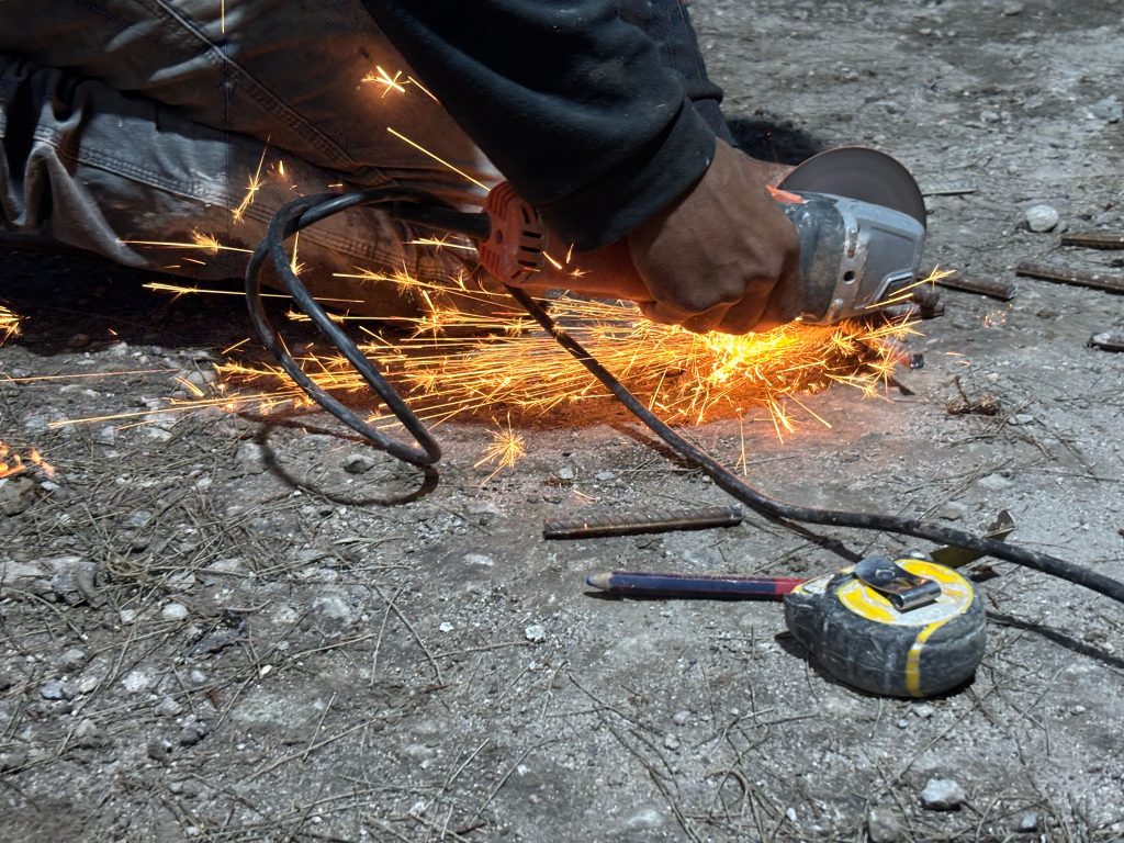 Worker using an angle grinder, with sparks flying across the ground