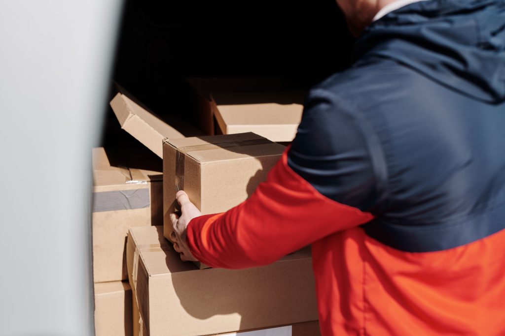 Person in a red and navy jacket lifting cardboard boxes